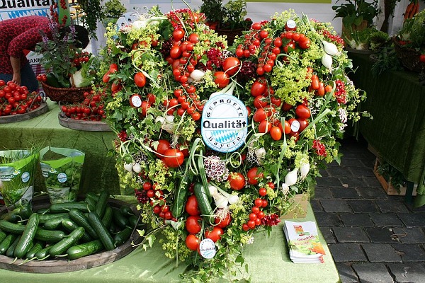 Herzförmiger Gemüsestrauch mit Tomaten, Gurken, Lauchzwiebeln und mehr auf Tisch bei der Bauernmarktmeile in Nürnberg.